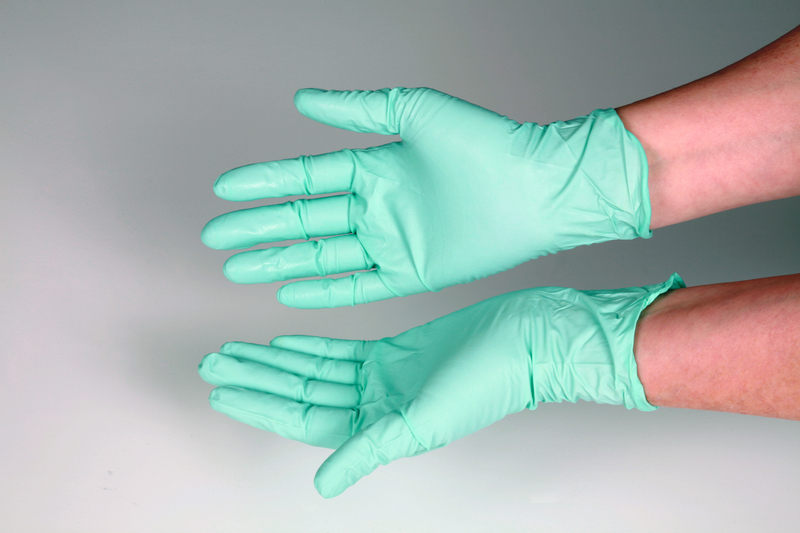 Closeup of hands in green medical gloves